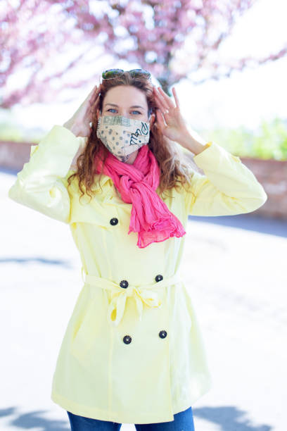 istock Happy young woman in mask posing outdoors during springtime sakura 1226041936