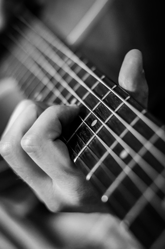 Guitar player chords close up on the strings - black and white, selective focus.