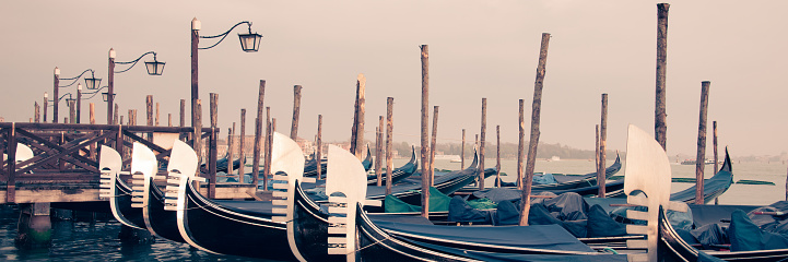 Panoramic view of gondolas and wooden pier in winter in Venice, Italy