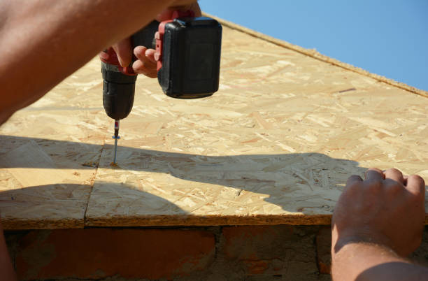 istock Roofer installing wooden board for asphalt shingles installation on house roof corner using screwdriver. Roofing construction. 1226046035