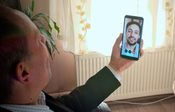 Modern father and son video chatting with phone, with plant on background stock photo