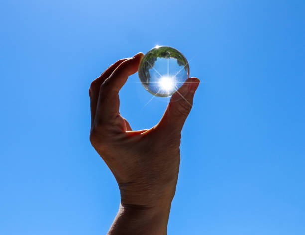 kobieca ręka trzymająca przezroczystą kryształową kulę z odbiciem miasta i drzew. - transparent crystal crystal ball human hand zdjęcia i obrazy z banku zdjęć