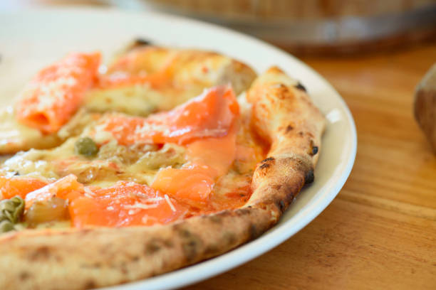 Homemade pizza with capers on a wood table