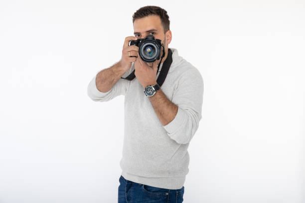 istock Photographer looking through the lens in studio. Isolated on white background. 1226055857