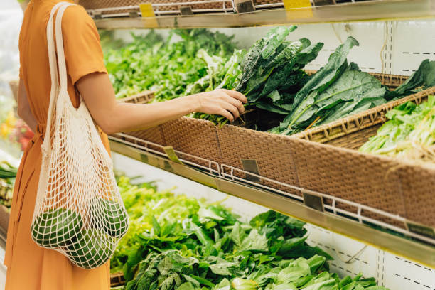 mädchen hält mesh-einkaufstasche mit gemüse ohne plastiktüten im lebensmittelgeschäft. - supermarket stock-fotos und bilder