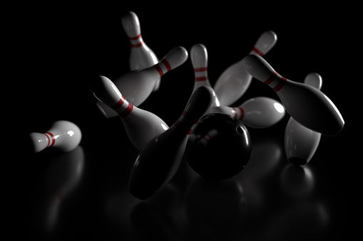 3D graphics of bowling ball and fallen skittles on the playing field (black background). shallow depth of field.