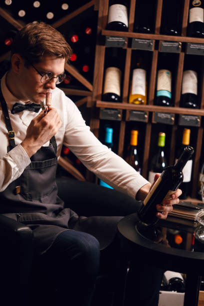 istock Sommelier opening a wine bottle with corkscrew in restaurant with wine shelves. 1226058407