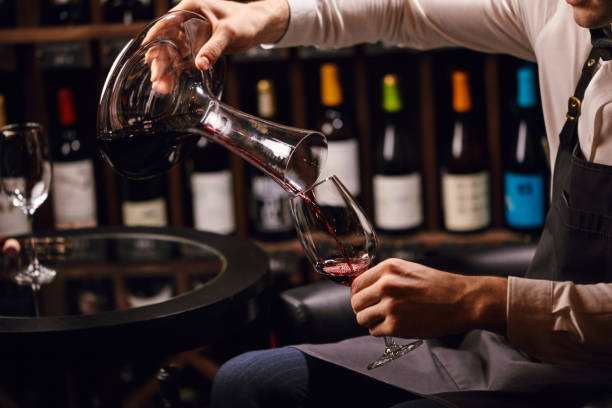 istock Skilled sommelier pouring wine from decanter ino wine glass. 1226058408