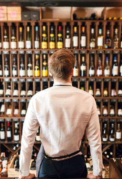 istock Backside of elegant wine seller selecting wine for customers in wine shop 1226058430