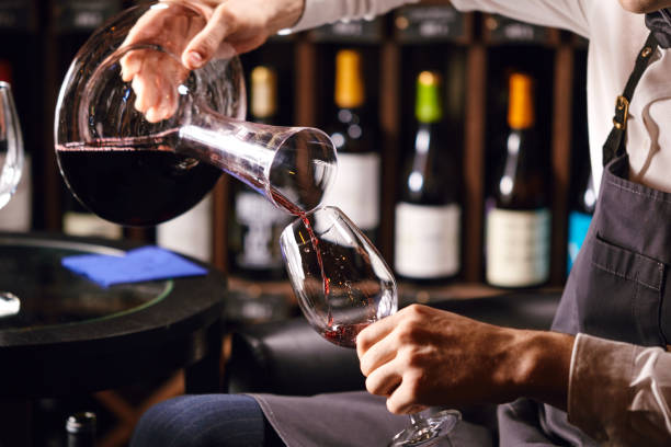 istock Skilled sommelier pouring wine from decanter ino wine glass. 1226059035