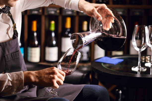 istock Skilled sommelier pouring wine from decanter ino wine glass. 1226059051