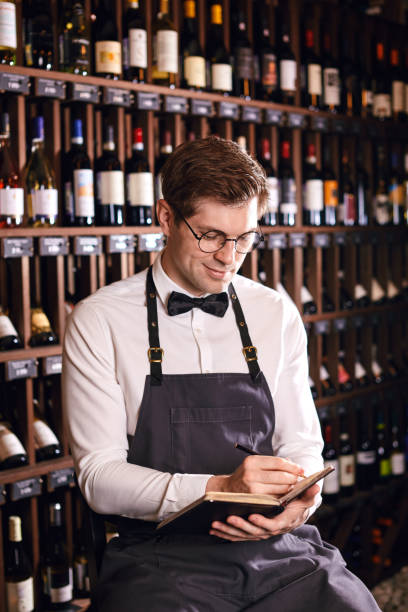 istock Male cavist examines the bottles with wine and making notes at his notepad 1226059198