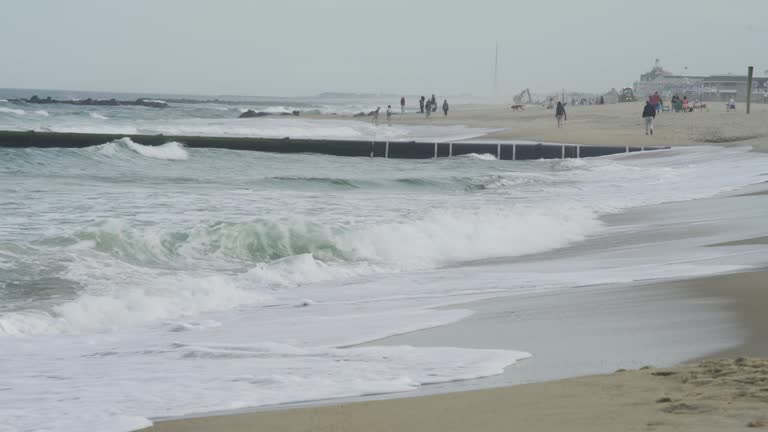 4K. Sandy coast. A big, foaming wave beating against the shore.