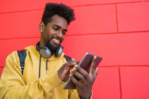 istock Afro man using his digital tablet with earphones. 1226060986