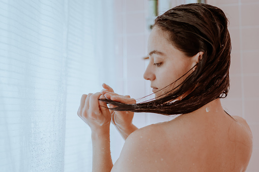 Mujer tomando una ducha y lavándose el pelo en casa photo