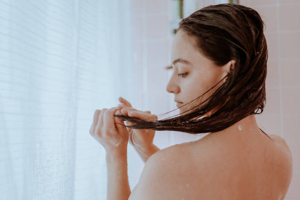 mujer tomando una ducha y lavándose el pelo en casa - shampoo fotografías e imágenes de stock