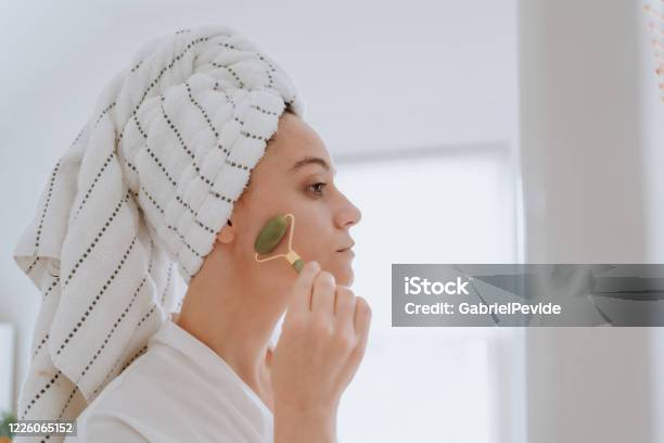 Woman Using Jade Roller On Her Face At Home Stock Photo - Download Image Now - Jade Roller, Women, Human Face