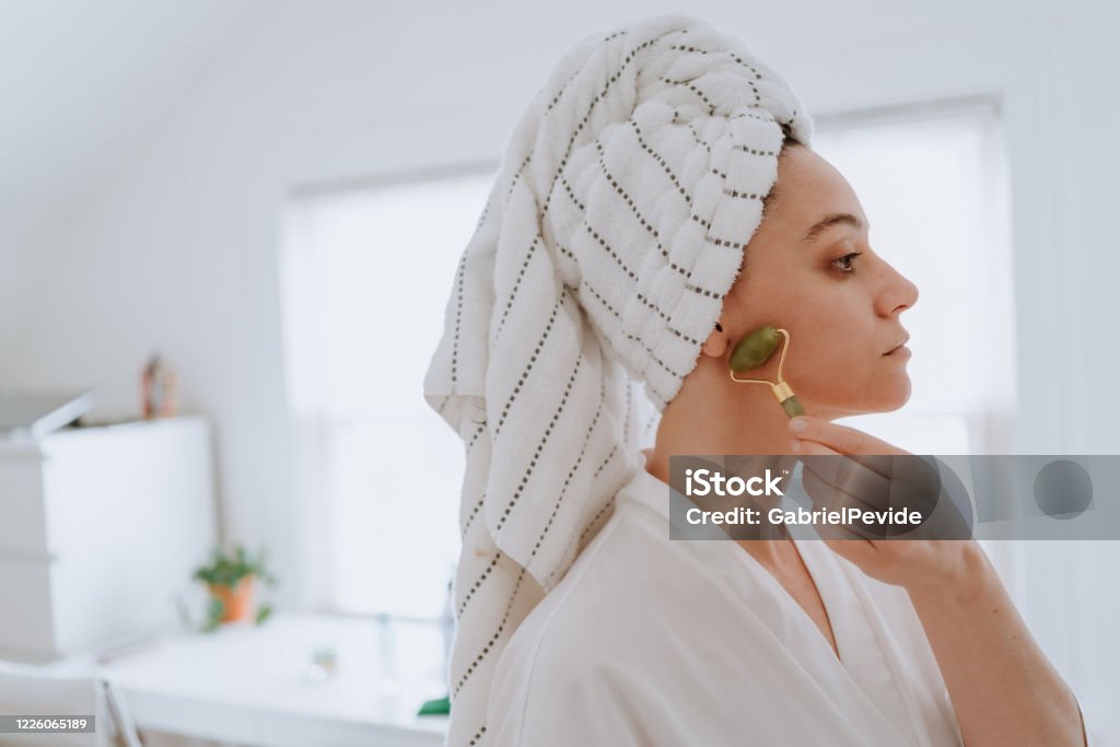 Woman using jade roller on her face at home Jade Roller Stock Photo