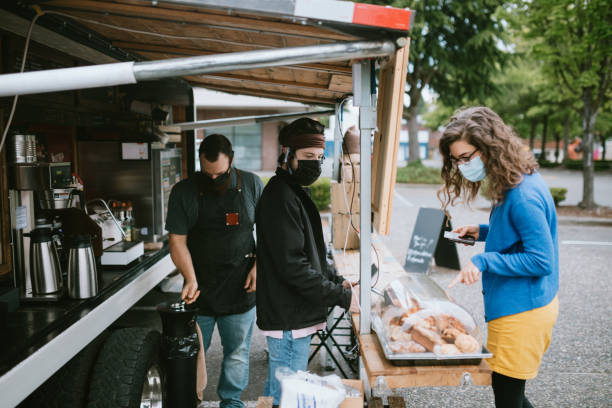 Masked Customer Orders Coffee And Snacks at Food Truck A young man takes the order of a woman at a coffee food cart in the Seattle, Washington area.  The outdoor setting is ideal for people to still purchase their coffee and espresso drinks while maintaining social distance during the Coronavirus pandemic. seattle photos stock pictures, royalty-free photos & images