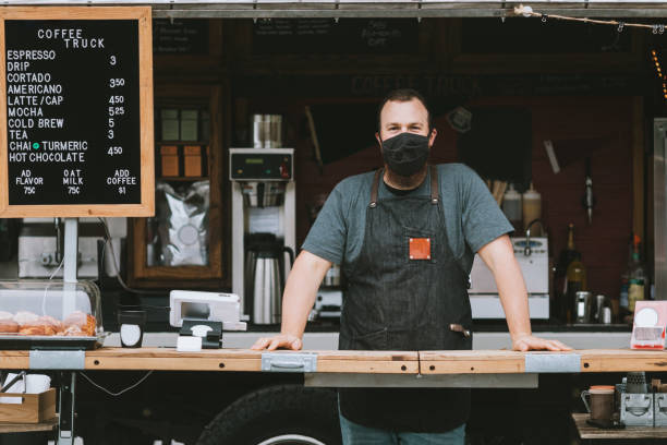 Food Truck Owner Wearing Protective Face Mask A mobile coffee truck is open for business during the Coronavirus pandemic.  The owner wears a mask during work hours. resilience photos stock pictures, royalty-free photos & images