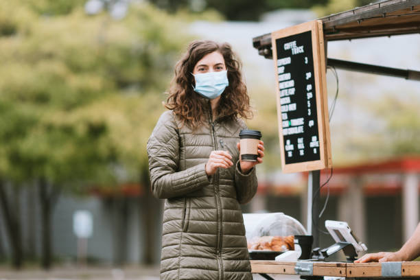 istock Cheerful Smiling Woman Wearing Face Mask Buys Coffee 1226065699