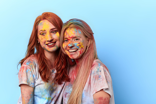 beautiful charming girls have attended festival of colours. close up portrait. isolated blue background. summer tradition and custom