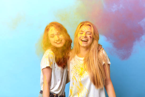 laughing two girls having fun on holiday, arrival of spring, the end of winter. isolated blue background, studio shot.