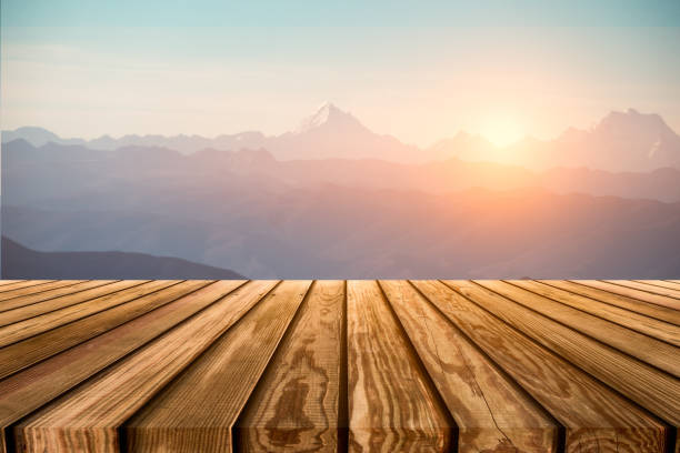 Brown wooden table top on blurred peak on mountain range with sunrise