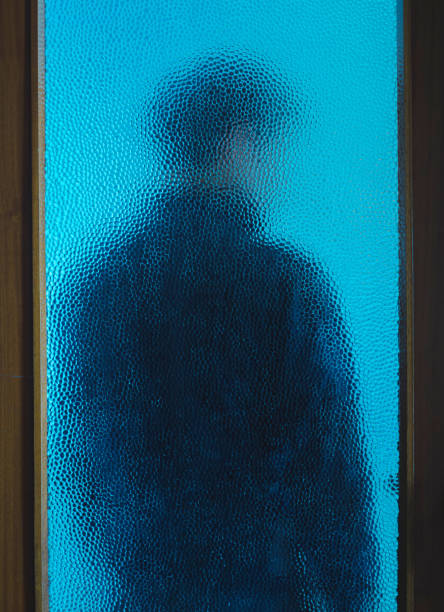 istock Man in black behind closed door through glass 1226068325