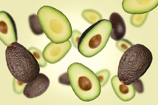 istock Falling brown avocados isolated on a green background with clipping path as package design element and advertising. 1226068736