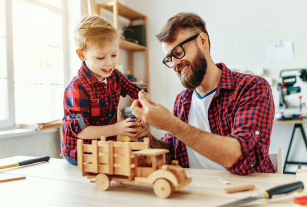 istock Cheerful man with kid making wooden toys in workshop 1226072279