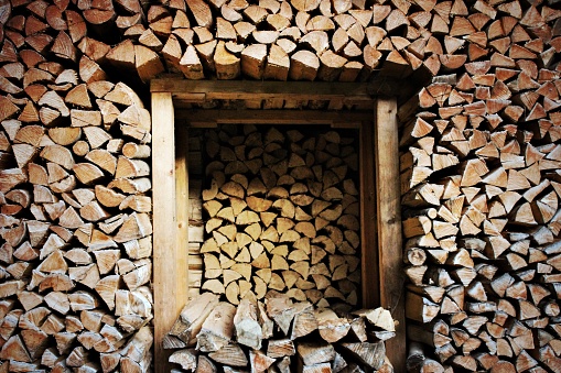 Stacked woodpile with triangular shaped logs at cross section and frame at the centre