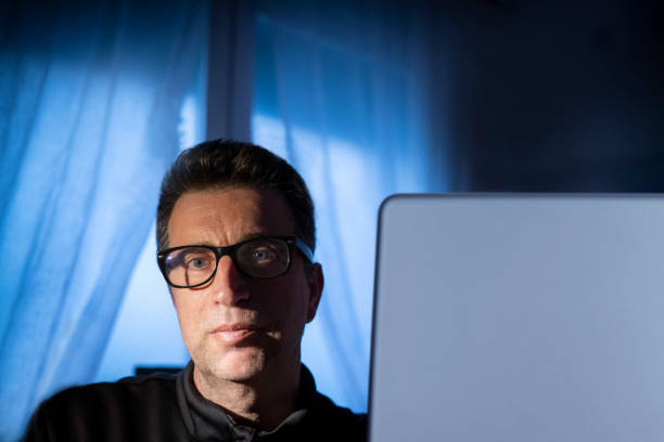 istock Adult man teleconferencing with computer with blue night light at home 1226073151