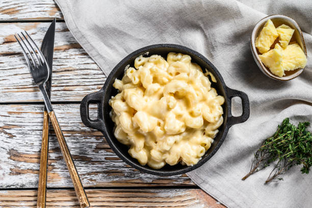 American mac and cheese, macaroni pasta in cheesy sauce.  White wooden background. Top view American mac and cheese, macaroni pasta in cheesy sauce.  White wooden background. Top view. cheese sauce stock pictures, royalty-free photos & images