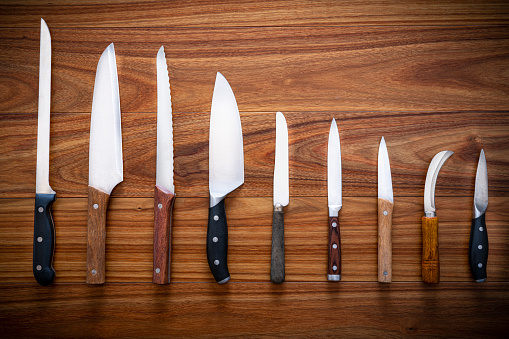 Kitchen knifes inventory on wooden backgroun in a row arrangement