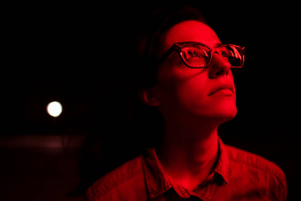 Young woman standing in dark while a red light shines on her face