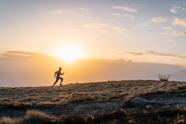istock Young man trail runs up mountain at sunrise 1226076436