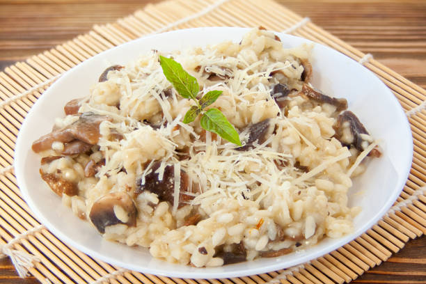 leckeres appetitliches risotto auf weißer platte auf holztisch - parmesan cheese risotto rice basil stock-fotos und bilder