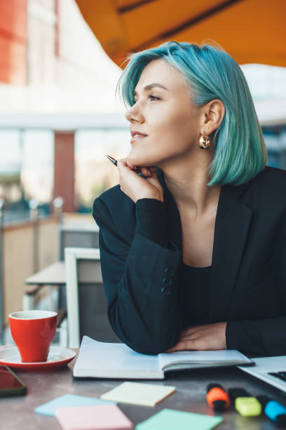 istock Pensive caucasian blue haired lady looking away while sitting in a coffee shop and making some notes 1226083749