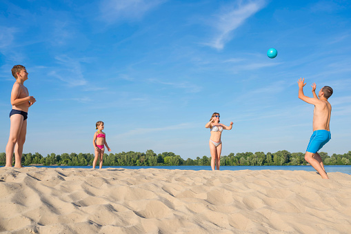 Happy family playing beach volleyball by the river on a sunny day. lifestyle. Summer holidays.