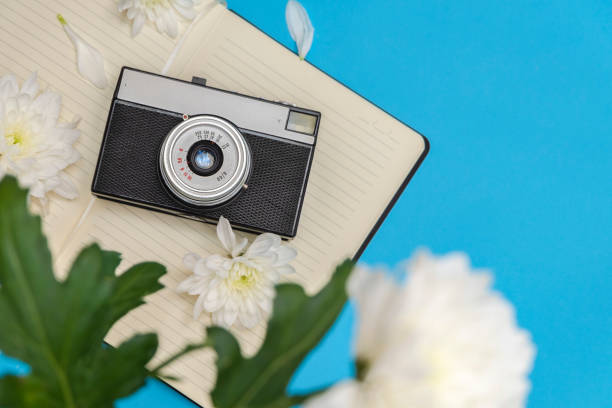istock Vintage retro photo camera with notebook and flowers on  light blue background 1226084022