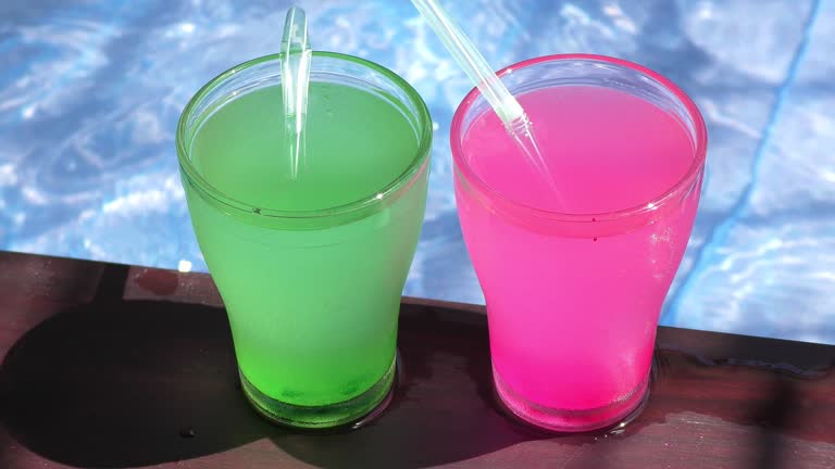 Two mocktail glasses on the sides of the pool water and straws.
