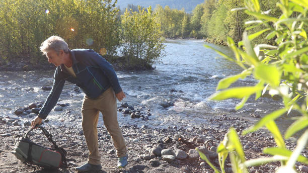istock Man relaxes by riverbank in the morning 1226084999