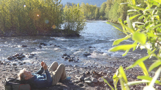 istock Man relaxes by riverbank in the morning 1226085109