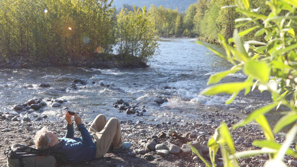 istock Man relaxes by riverbank in the morning 1226085234