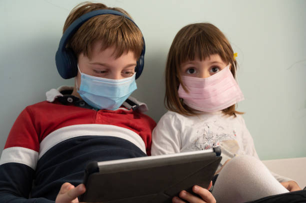 istock Brother and sister with masks at home 1226086462