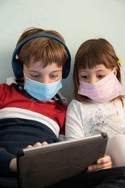 istock Brother and sister with masks at home 1226086539
