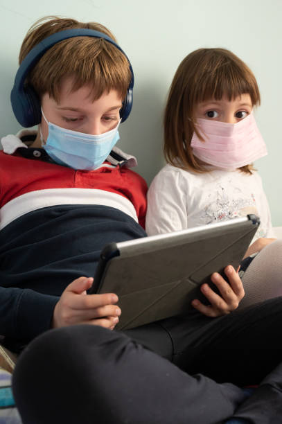istock Brother and sister with masks at home 1226086592