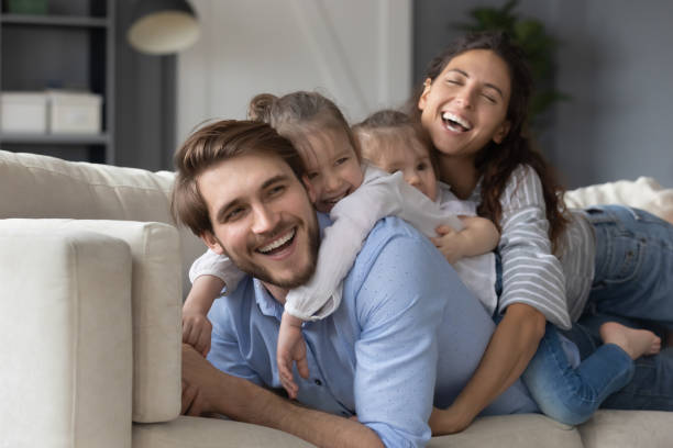 istock Overjoyed young parents relax on sofa with little daughters 1226087887