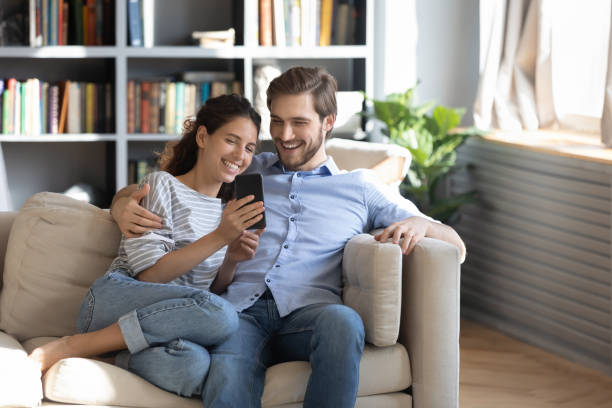 Happy young couple using smartphone at home